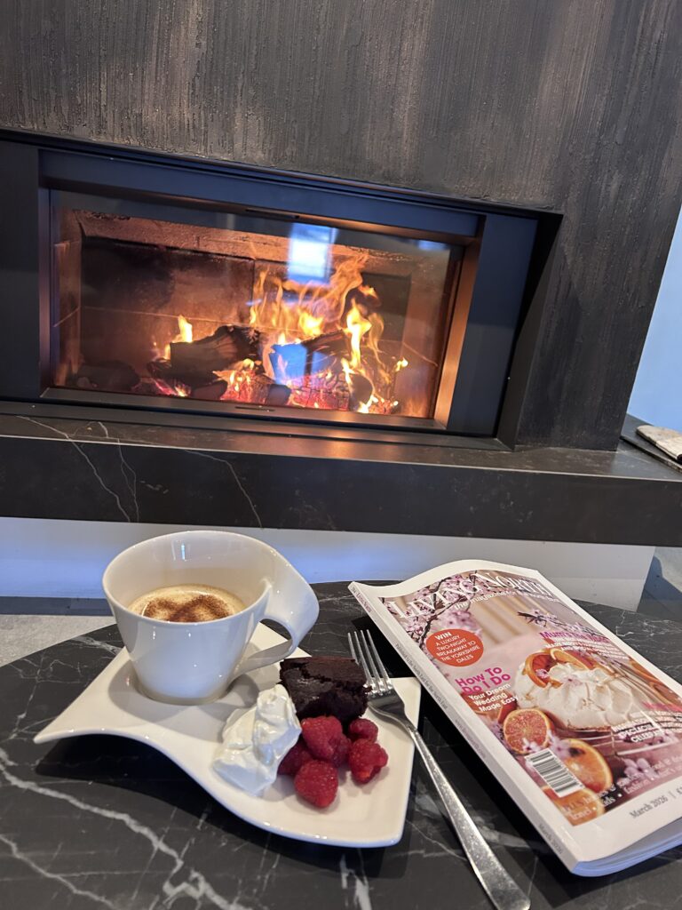 Coffee and chocolate brownie infront of wood-burning stove while reading living north magazine